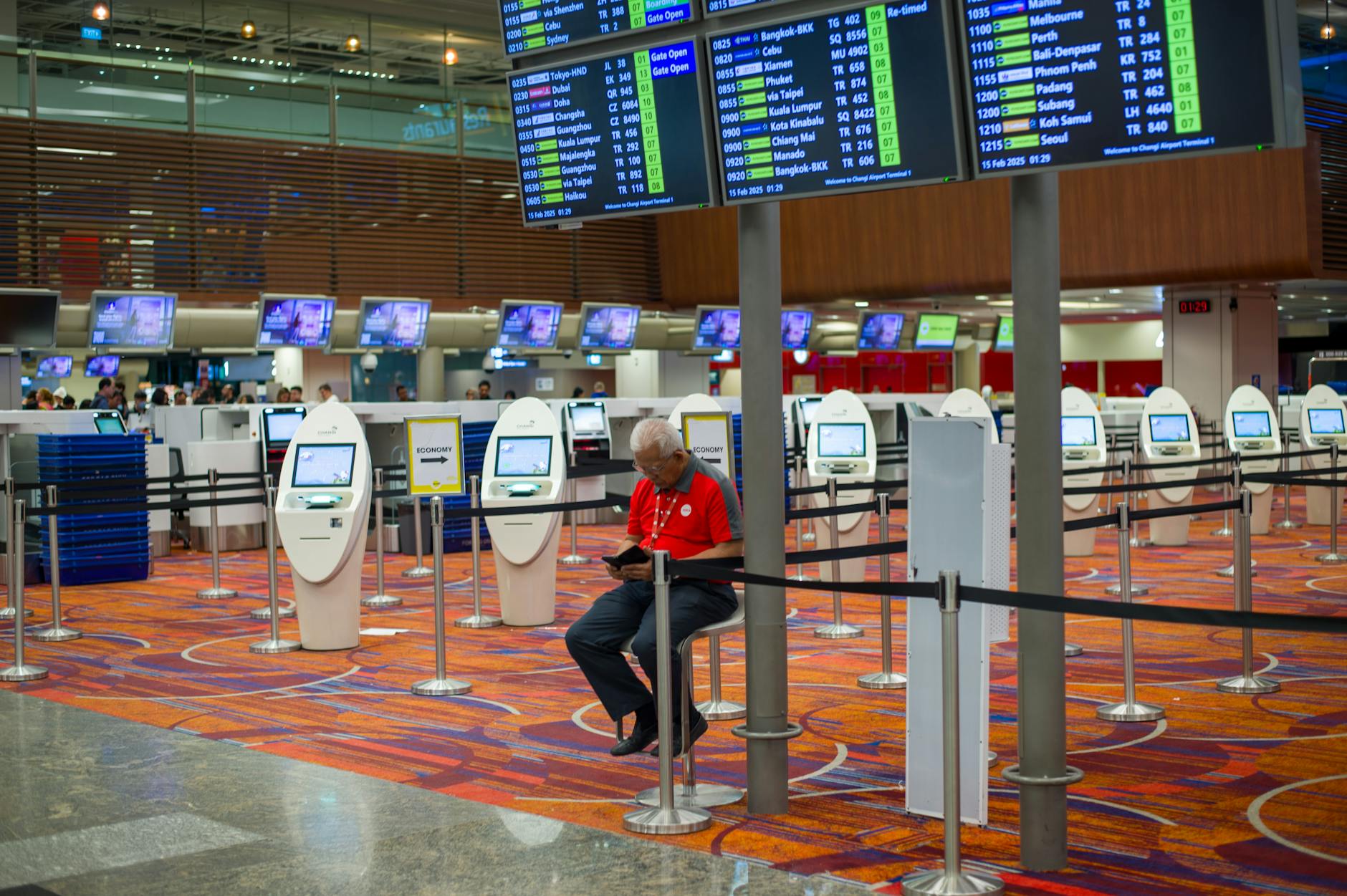 Ruchliwy terminal lotniska z ekranami lotów i samoobsługowymi kioskami